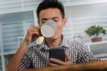 Young man asian using mobile phone working from home after coronavirus or covid-19 pandemic