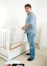Young man assembling furniture in baby`s room Royalty Free Stock Photo