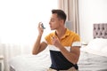 Young man with asthma inhaler on bed Royalty Free Stock Photo