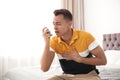 Young man with asthma inhaler on bed Royalty Free Stock Photo