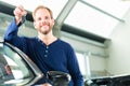 Young man with auto in car dealership Royalty Free Stock Photo