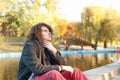 Young man autumn outdoor portrait sitting against autumn lake in park Royalty Free Stock Photo