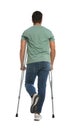 Young man with axillary crutches on white background, back view