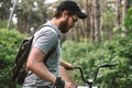 Young man with backpack cycling on a forest path, active lifestyle