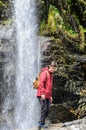 Young man with backpack in front of a waterfall