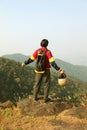 Young man with backpack and helmet standing with raised hands on top of a mountain and enjoying valley view Royalty Free Stock Photo