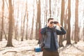 Young man with backpack looking at the binoculars, hiking in the forest Royalty Free Stock Photo