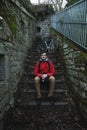 Young man with backpack outdoors, sitting on stairs