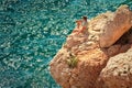 Young Man with backpack relaxing on rocky cliff with blue Sea on background Royalty Free Stock Photo