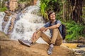 Young man with backpack standing near a waterfall in forest. Male hiker in the nature Royalty Free Stock Photo