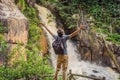 Young man with backpack standing near a waterfall in forest. Male hiker in the nature Royalty Free Stock Photo