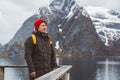 Young man with a backpack standing on a wooden pier the background of snowy mountains and lake. Place for text or advertising Royalty Free Stock Photo