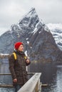 Young man with a backpack standing on a wooden pier the background of snowy mountains and lake. Place for text or advertising Royalty Free Stock Photo