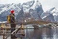 Young man with a backpack standing on a wooden pier the background of snowy mountains and lake. Place for text or advertising Royalty Free Stock Photo