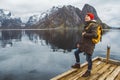 Young man with a backpack standing on a wooden pier the background of snowy mountains and lake. Place for text or advertising Royalty Free Stock Photo