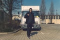 Young man with backpack stands in front of a truck