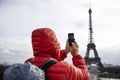 Young man with backpack taking photograph with mobile phone of E