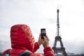 Young man with backpack taking photograph with mobile phone