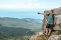 Young man with a backpack on top of cliff enjoying view of nature. Mountains and sea Royalty Free Stock Photo