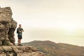 Young man with a backpack on top of cliff enjoying view of nature. Mountains and sea Royalty Free Stock Photo