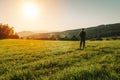 Young man with backpack walking on meadow in summer Czech landscape at sunset Royalty Free Stock Photo