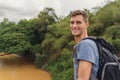 Young man with backpack is whatching the river in Botanical Garden of Sri Lanka