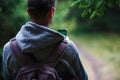 A young man with a backpack in the woods looking at the phone-a view from the back. Royalty Free Stock Photo