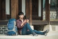 Young man backpacking in Korea. sitting in a Korean traditional house and using a tablet computer. Royalty Free Stock Photo