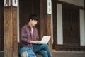 Young man backpacking in Korea. using a laptop sitting in a Korean traditional house. Royalty Free Stock Photo