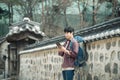Young man backpacking in Korea. Using a tablet computer leaning against a wall