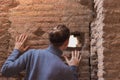 Young man backwards peeking curiously through hollow of historical brick ruin Royalty Free Stock Photo