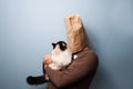 Young man with bag over head holding his cat