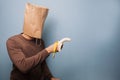 Young man with bag over his head using banana as gun Royalty Free Stock Photo