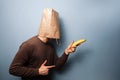 Young man with bag over his head using banana as gun Royalty Free Stock Photo