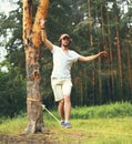 young man balancing his arms walk on a loose rope tied between two trees, male training slack rope walking, slacklining outdoors Royalty Free Stock Photo