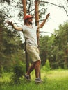 Young man balancing his arms walk on a loose rope tied between two trees, male training slack rope walking, slacklining in summer Royalty Free Stock Photo
