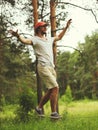 Young man balancing his arms walk on a loose rope tied between two trees, male training slack rope walking, slacklining in summer