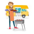 Young man barbecuing meat in front of camper van.