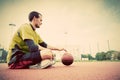 Young man on basketball court. Sitting and dribbling