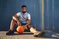 Young man with basketball doing exercise outdoors in city, sitting and resting. Royalty Free Stock Photo