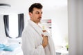 Young man with bathrobe in the bedroom, a morning routine. Royalty Free Stock Photo