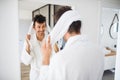 Young man with bathrobe in the bedroom, a morning routine.