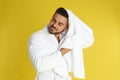 Young man in bathrobe drying hair with towel on yellow Royalty Free Stock Photo