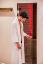 Young man in bathrobe entering or exiting sauna