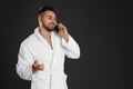 Young man in bathrobe talking on mobile phone against background. Space for text Royalty Free Stock Photo