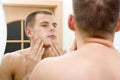 Young man in the bathroom's mirror after shave