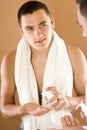 Young man in the bathroom's mirror using cream Royalty Free Stock Photo