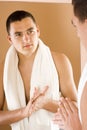 Young man in the bathroom's mirror using cream Royalty Free Stock Photo