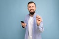 A young man with a beard on the background of a blue wall shows a gesture delicious