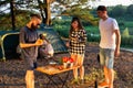 A young man with a beard and black glasses is preparing a salad of vegetables in nature in the company of friends. Outdoor Royalty Free Stock Photo